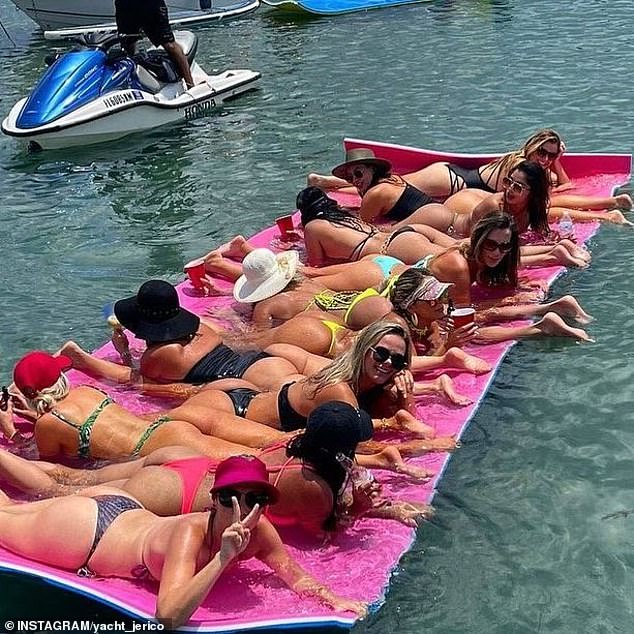 A group of bikini-clad women were seen lounging face down on a long pink float in the crystal blue water.