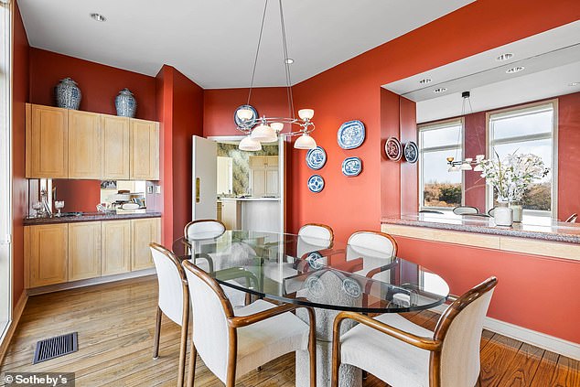 The dining room has a wooden floor that adds a touch of elegance to the red-walled room.