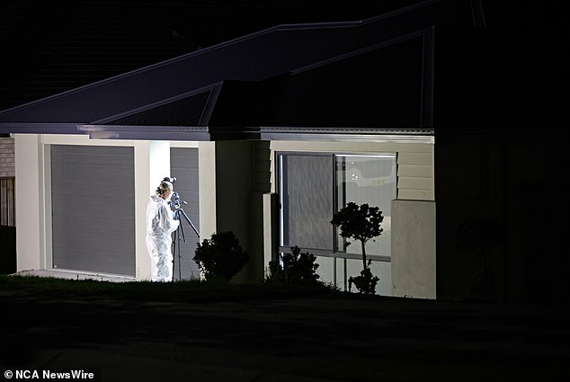 A forensic officer photographs the house where the sisters lived with two adult women, one of whom is believed to be their mother, in the four-bedroom rental.