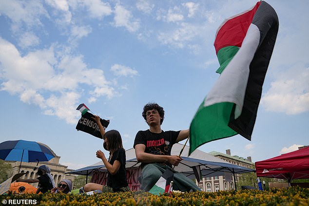 A protester holds a Palestinian flag as students gather on the Columbia University campus in a protest camp in support of the Palestinians, despite a 2 p.m. deadline issued by university officials to disband or confront a suspension.