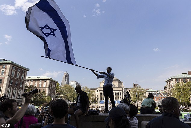 Columbia sophomore David Lederer waves a large Israeli flag in front of the student protest camp on the Columbia University campus, Monday, April 29, 2024.