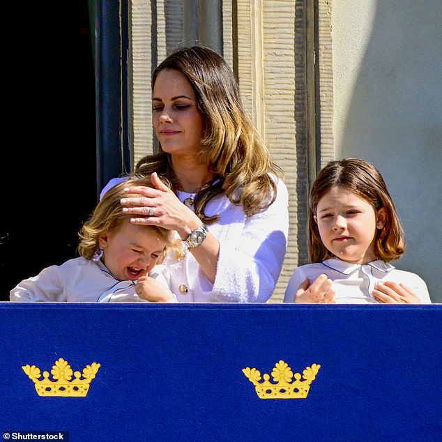 Princess Sofia comforts her youngest son who goes out to the royal balcony today restlessly