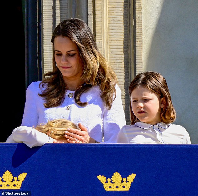 Three-year-old Prince Julian snuggles into his mother's chest on the balcony of the royal palace in Stockholm today.