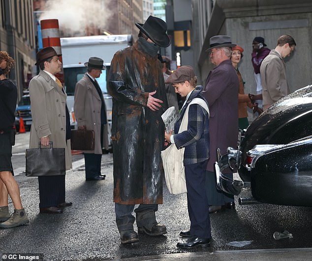 Joseph, who goes by the name 'Rex', wore a similar outfit to the other extras seen on set, wearing a dark plaid jacket and a flat cap.