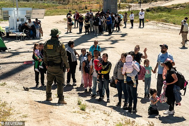 In January 2022, more than 11 million illegal immigrants were estimated to be living in the United States, Trump predicts, now it has reached 15 million under Biden's border crisis.  Pictured: Asylum seekers line up near the southern border after crossing illegally from Mexico into Texas.