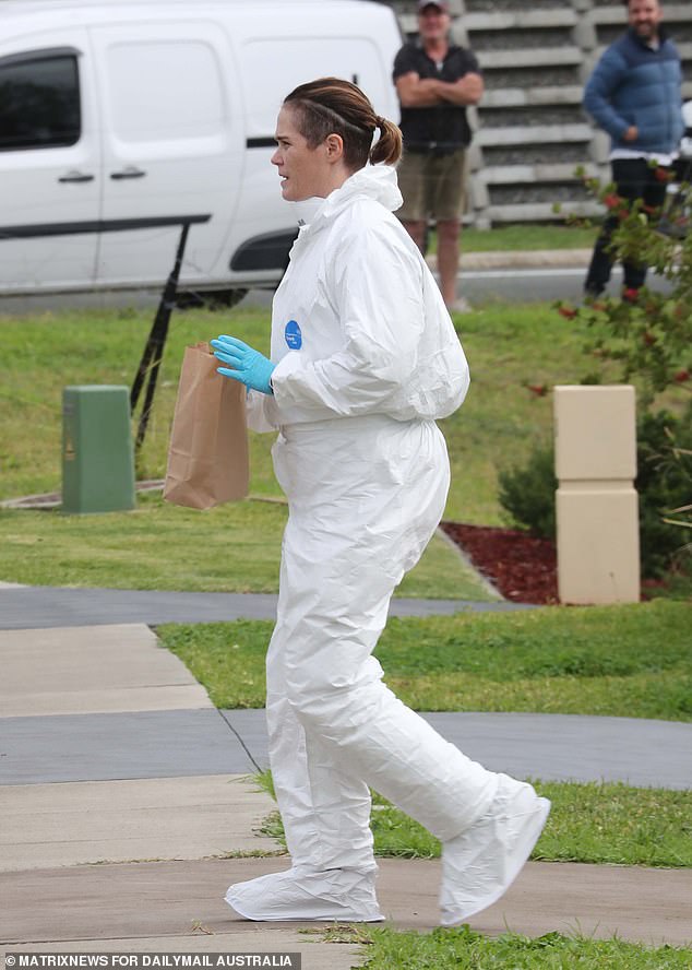 Pictured: A forensic investigator with a bag of evidence at the home on Tuesday.