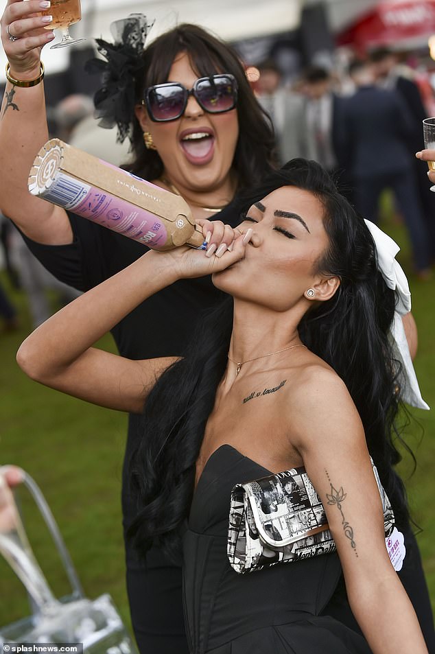 More light-hearted scenes: A woman is shown drinking from the bottle as her friend cheers her on in Liverpool today.
