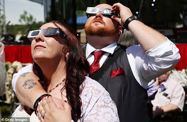 Four hundred couples said 'I do' at a mass wedding on a football field in Arkansas moments before the moon blocked the face of the sun in a rare celestial phenomenon.
