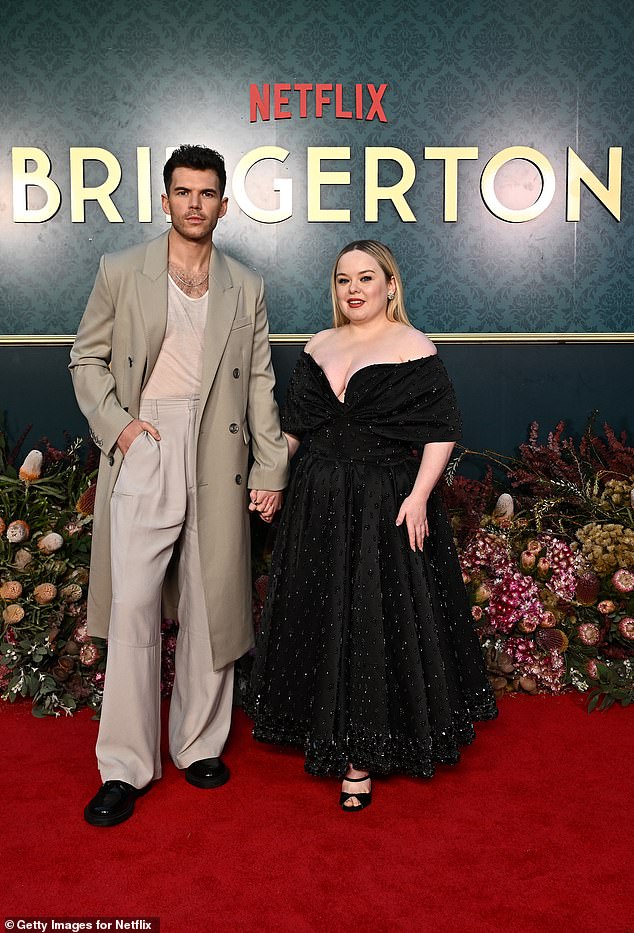The Irish actress opted for a sparkly black dress as she posed alongside co-star Luke Newton (pictured) in the grounds of Milton Park Country House.