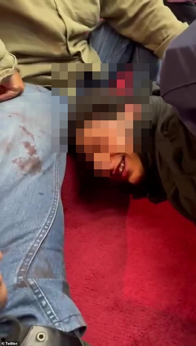 Footage has emerged of the alleged attacker being pinned face down by at least three people, including a police officer, while he smiled and appeared to mock his captors.
