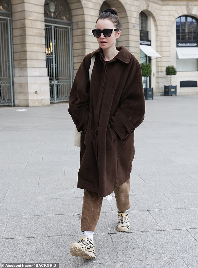 Lily Collins cut a casual figure in an oversized long brown coat and matching corduroy pants as she stepped out in Paris on Sunday.