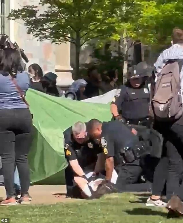 Two officers are seen restraining a student at Emory University Thursday morning.