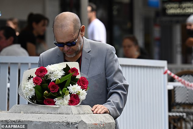 Pictured: A mourner places flowers as he pays his respects to the victims of the horrific attack in Bondi Junction on Saturday.