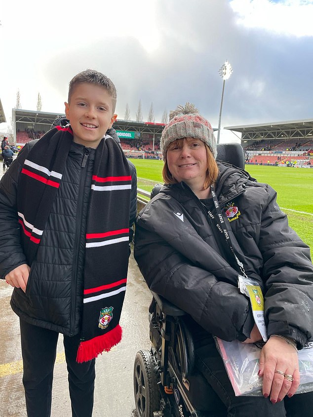Wrexham fan Theo Smith, 10, poses with Kerry Evans, right, who established a 120-seat section at the Racecourse Ground so fans with autism and physical challenges can watch football.
