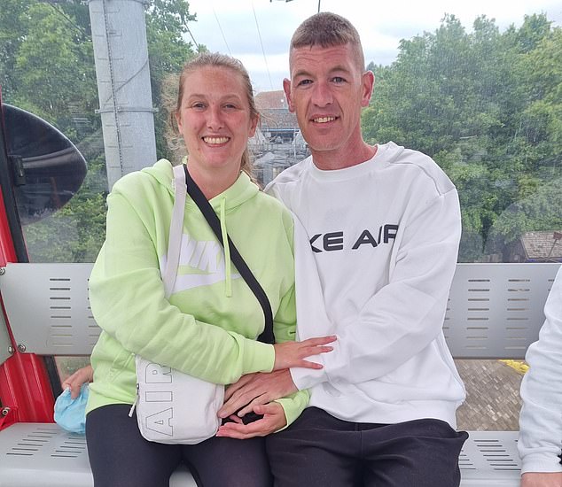 Mark Downey, 45, from Bolton, Manchester, pictured with his partner Samantha Scott, 39, suffered an excruciating headache while driving with his family to a holiday in Wales in September 2023.