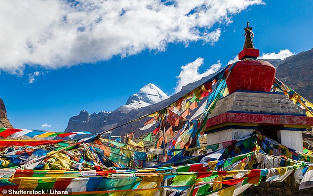 Colorful prayer flags flutter in the wind, with the south face of Mount Kailash in the background.