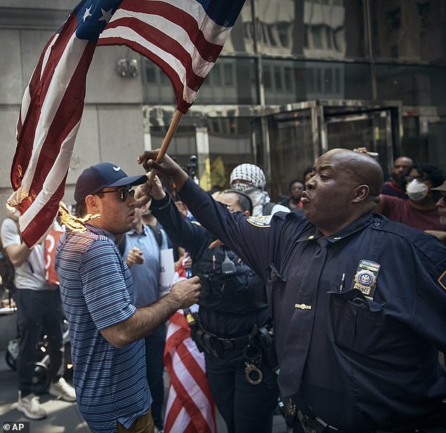 Police try to save a pro-Israel supporter, center, by removing his American flag that another person set on fire during a pro-Palestinian demonstration.