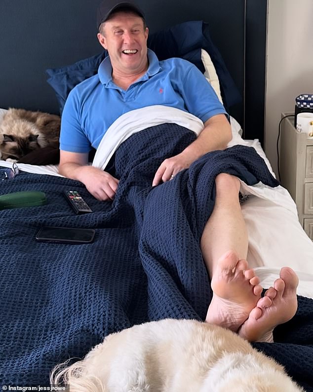 Jess Rowe has shared the news that her husband Peter Overton is currently recovering at home after recently undergoing hip replacement surgery.  In the photo: Peter in bed with the family pets.