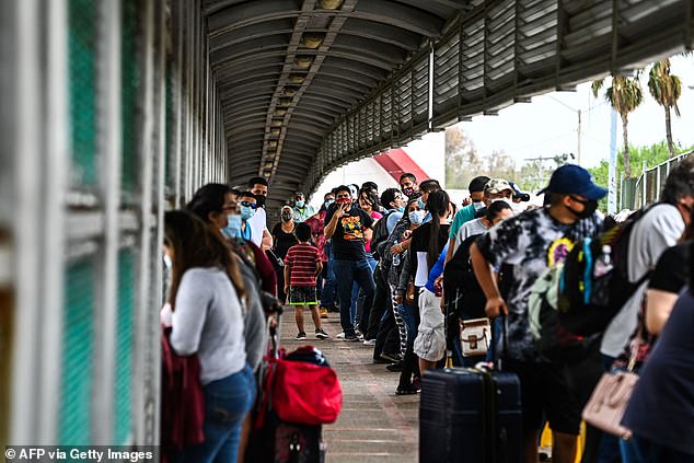 Migrants mostly from Central America wait in line to cross the border at the Gateway International Bridge into the US from Matamoros, Mexico.