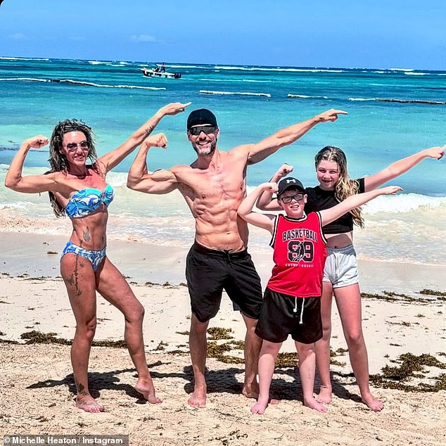 Michelle Heaton and husband Hugh Hanley showed off their ripped physiques as they posed in swimsuits on the beach during a family getaway to the Caribbean on Monday (pictured with kids Faith, 11, and AJ, nine).