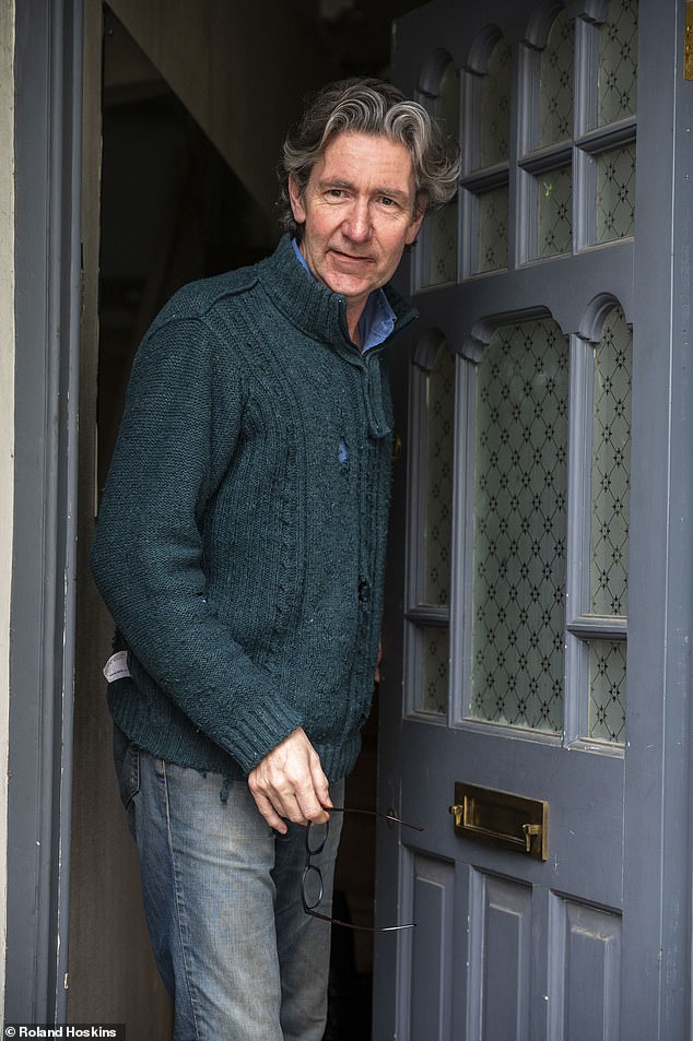 Lloyd Evans poses for a photograph for MailOnline outside his home in east London on Thursday.