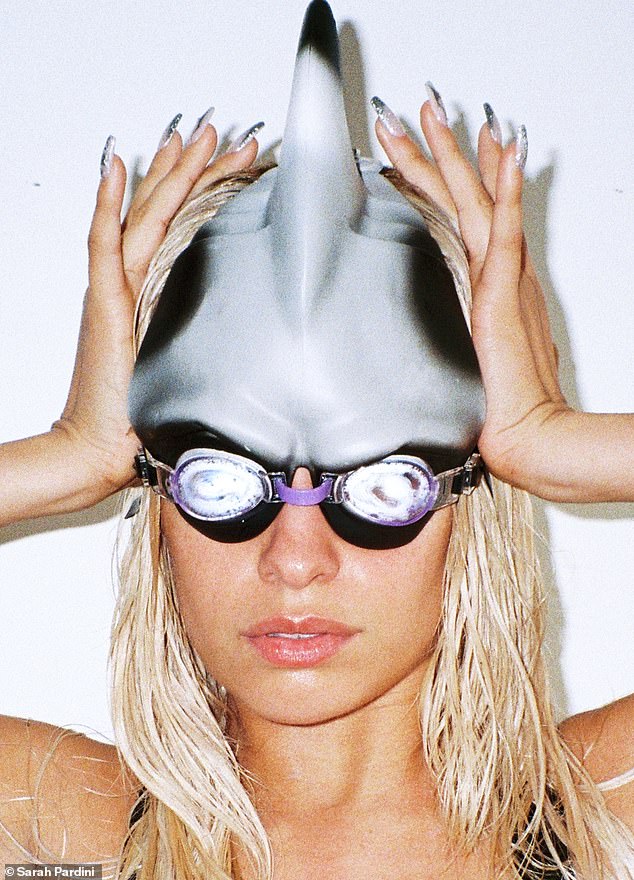 In one image, she sported a shark-inspired gray swim cap and eye-catching purple glasses while showing off her sparkly nails.