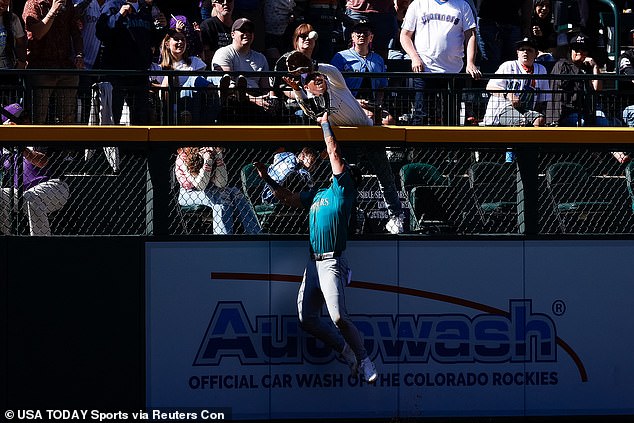A fan interferes with the ball on Seattle Mariners left fielder Jonatan Clase (5) in the ninth inning.