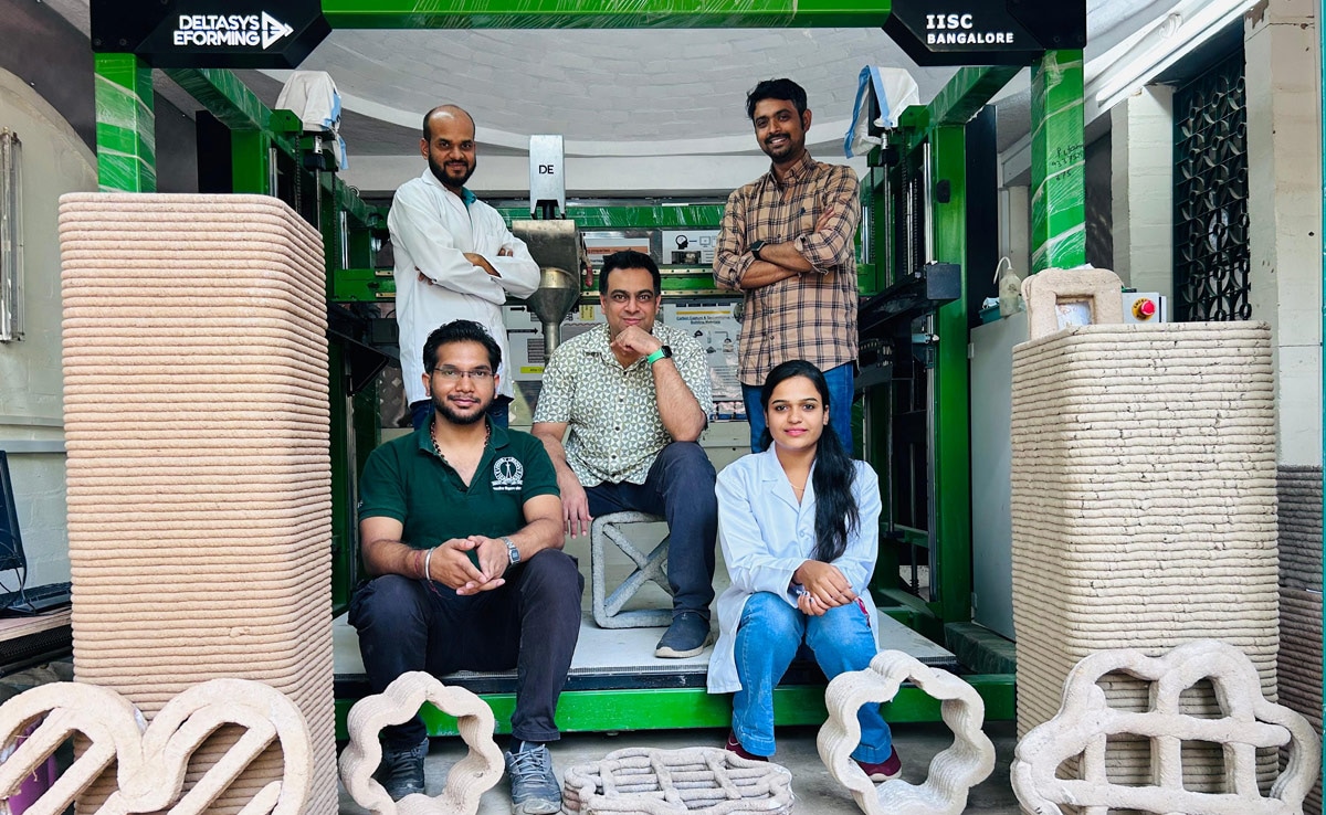 The lab members are seen surrounding the engineered carbon-captured building materials, which are manufactured using additive manufacturing. 