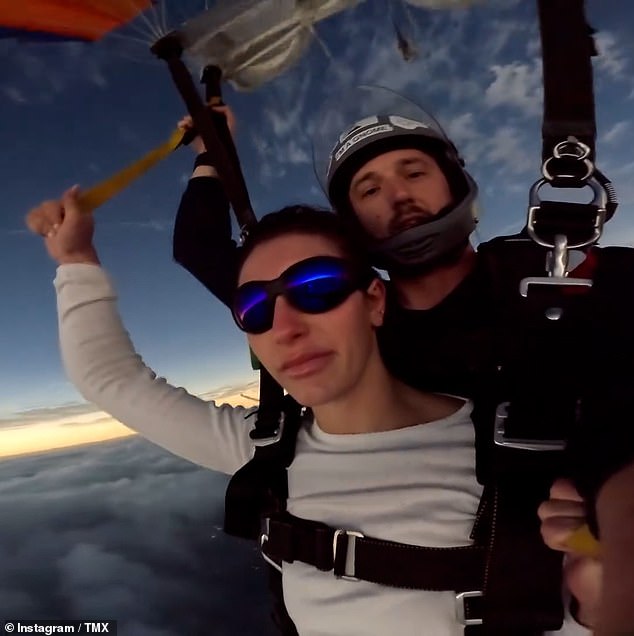 The lucky skydivers can be seen free-falling from 14,000 feet before the camera shows them floating with a parachute as the rare celestial event of the eclipse darkens the sky.