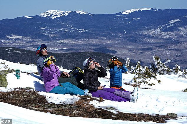 A family watches the solar eclipse from Saddleback Mountain in Rangeley, Maine, on Monday, April 8, in one of the last viewings of the day.