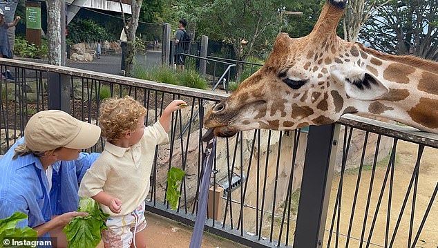 In one photo, the mother of two is seen helping her son feed a giraffe.