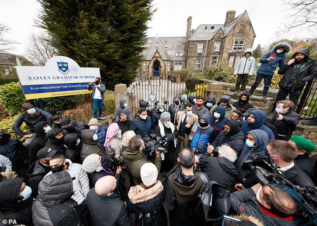 Protesters give a statement to members of the media outside Batley Grammar School in Batley, West Yorkshire