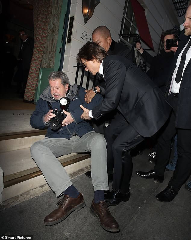 Tom Cruise stopped to help a photographer who fell to the ground as the movie star arrived at Victoria Beckham's 50th birthday party on Saturday.