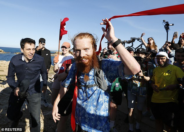 Russ Cook smiles as he crosses the finish line after becoming the first person to run across Africa