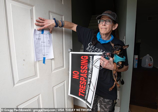 Carrie Black-Phillips, whose family owns property in Milton, Florida, points to a possession warrant now posted on the house as she cleans up the mess left by the squatters.