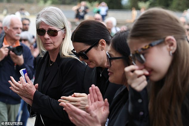 Nilsson and other mourners wipe away tears as they approach the church entrance.