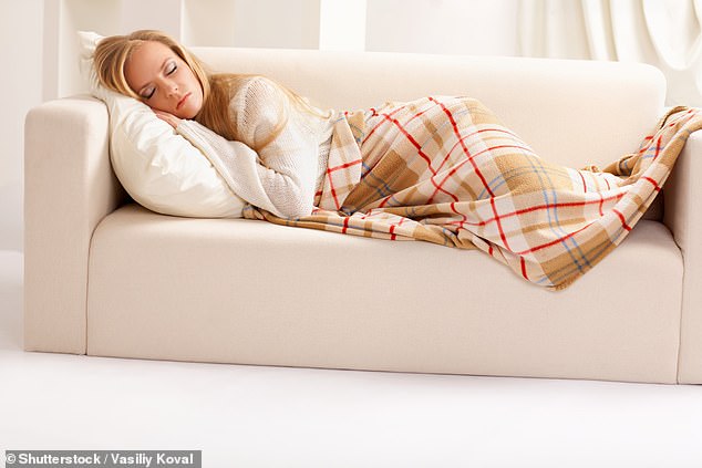 A woman sleeping on a sofa under a blanket.  Scientists say weighted blankets trigger the release of feel-good chemicals in the brain, which reacts to the pressure of the blanket as it would to a hug or hug (file image)