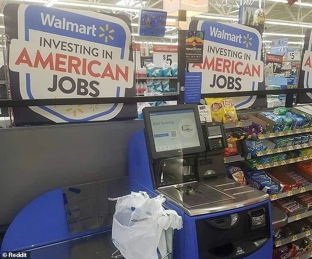 A photo of Walmart self-checkout machines ironically placed next to a sign stating that the company is 