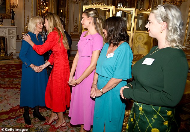 Queen Camilla shakes hands with Carrie Johnson while hosting a reception for the relaunch of The Wash Bags Project.
