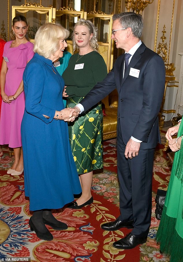 Queen Camilla shakes hands with a guest as she hosts a reception in recognition of those who support survivors of sexual assault.