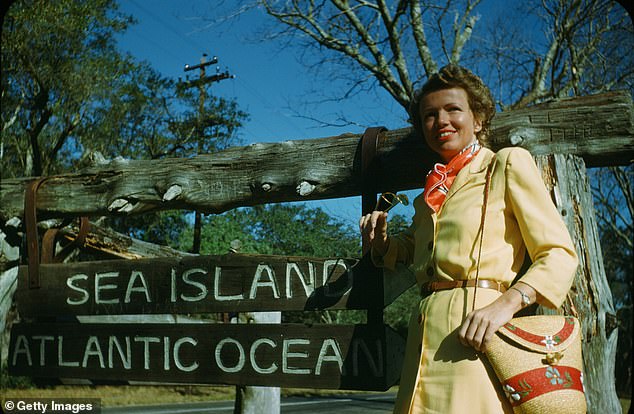 A woman poses in front of the wooden sign of Sea Island and the Atlantic Ocean in Georgia circa 1949.