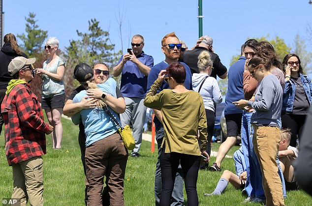 People gather at a site designated for parent and student reunifications following a report of an armed person outside Mount Horeb High School.