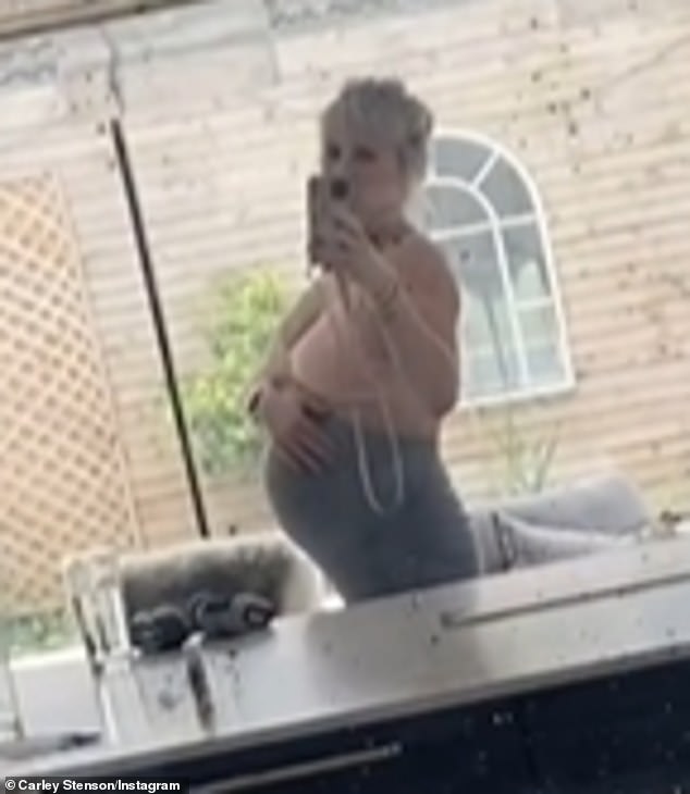 The pregnant former Hollyoaks star, 41, cradled her baby bump while wearing a pink sports bra and a pair of gray leggings.