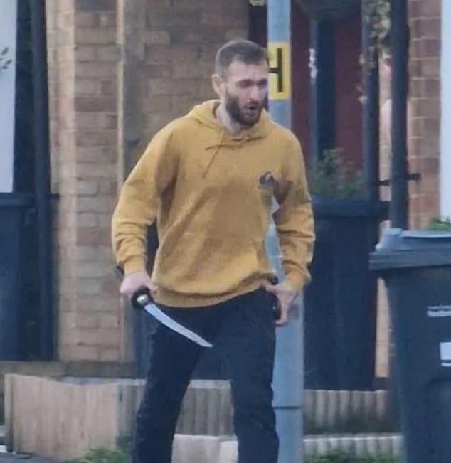 A photo of a man holding a sword while prowling the streets of Hainault on Tuesday.