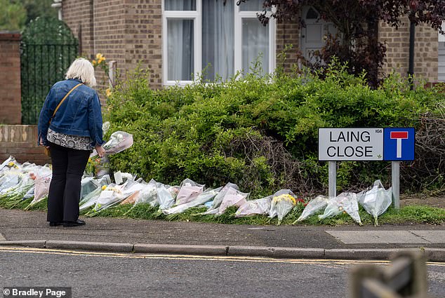 A woman leaves flowers in memory of Daniel at a police cordon near the scene in Hainault today