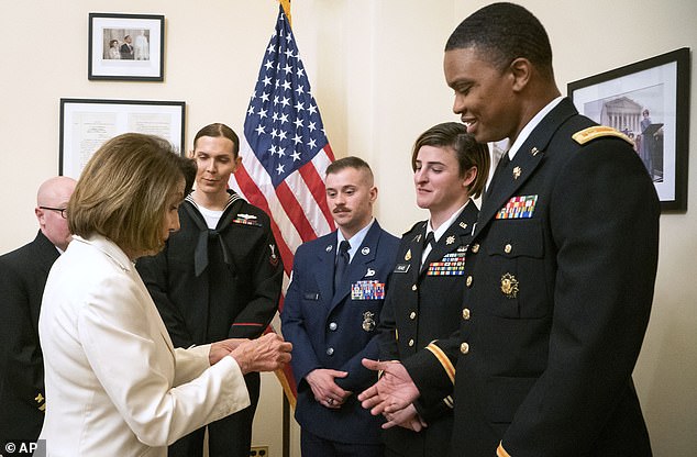 Former House Speaker Nancy Pelosi (D-Calif., left) presents challenge coins to U.S. Army Maj. Ian Brown, right, and other military service members in 2019 to thank them for their service.  Brown, 38, is a two-time Bronze Star recipient and transitioned from woman to man while advising the Army deputy chief of staff on operations and planning.