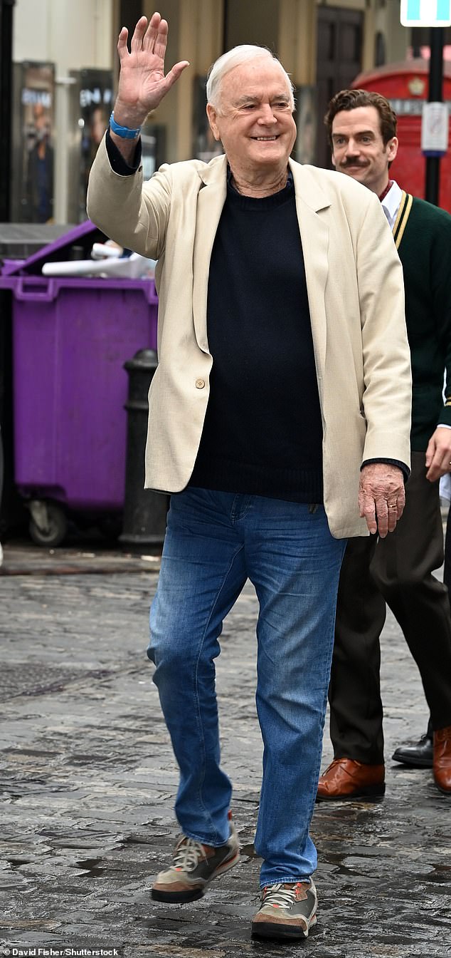 John Cleese was all smiles as he arrived at the West End show preview wearing a pair of blue jeans with dark brown and gray trainers, a plain black t-shirt and a light beige jacket.