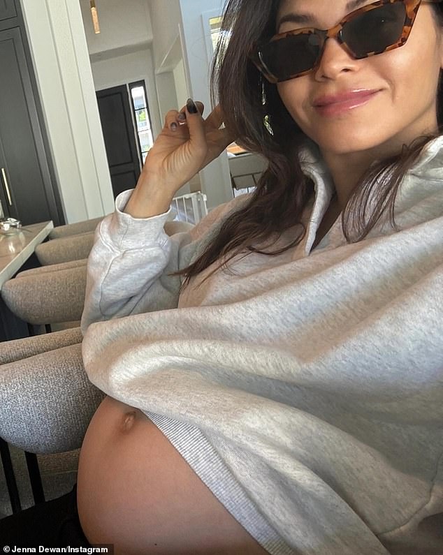 The fourth was a cute photo of her smiling and wearing sunglasses with her gray hoodie pulled up to expose her belly.