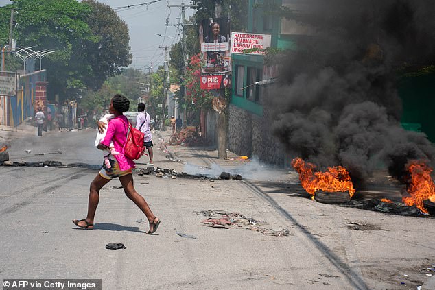 A woman carrying a child flees the area after gunshots were heard in Port-au-Prince, Haiti, on March 20.