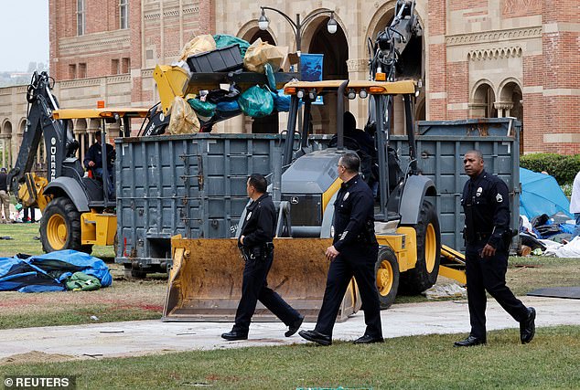 Police pass by as people work to clean up trash left by anti-Israel protesters at UCLA
